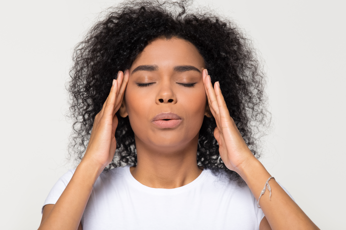 woman holding her head, appears as though it hurts.