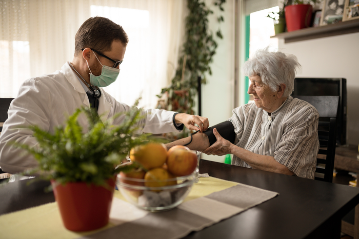 Older adult woman with doctor checking blood pressure