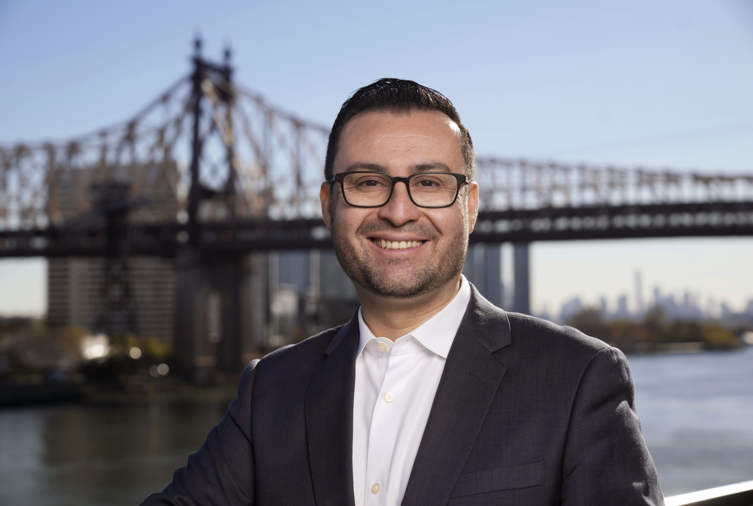 A man posing for a photo with the 59th street bridge in the background