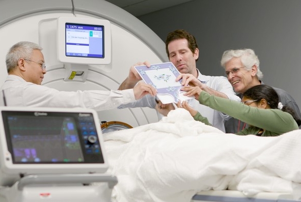 A group of people evaluate a patient in an MRI machine