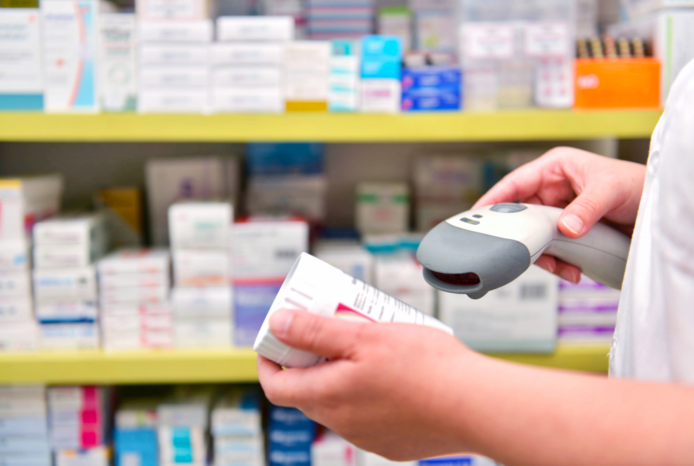 hands holding scanner and pill bottle
