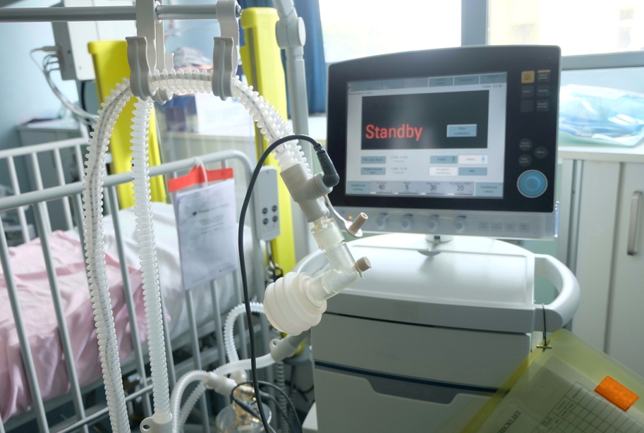 ventilator monitor reading &#039;standby&#039; in foreground with hospital bed in background