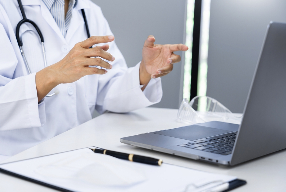 physician speaking to laptop using telehealth