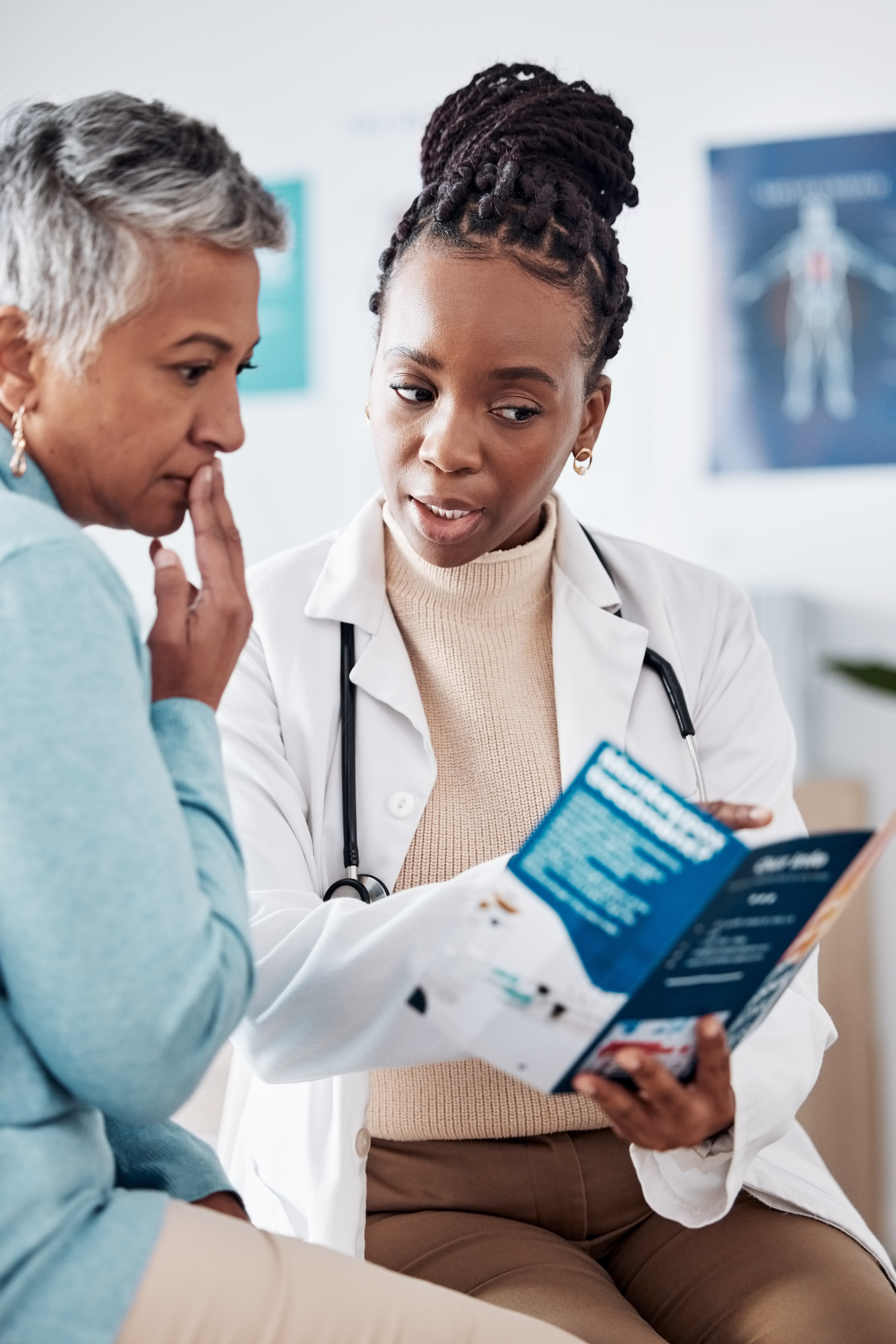 woman wearing stethoscope reading from patient brochure for female patient