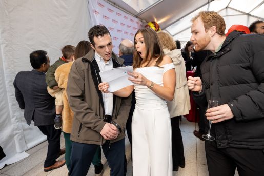A woman wearing a white dress standing next to a man at an event