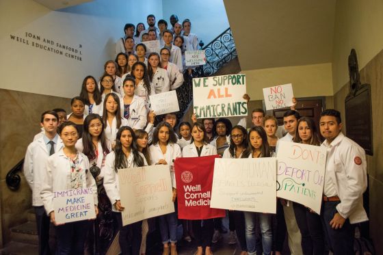 In fall 2017, WCM student activists gathered for a group photo in support of immigrants and refugees; participants included Nneoma Adaku (at center right, holding a sign over her head), co-founder of White Coats for Black Lives. students standing in solidarity