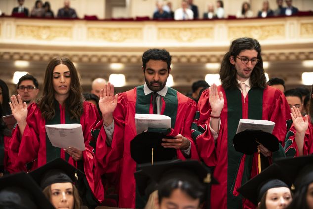 Students in graduation regalia giving an oath