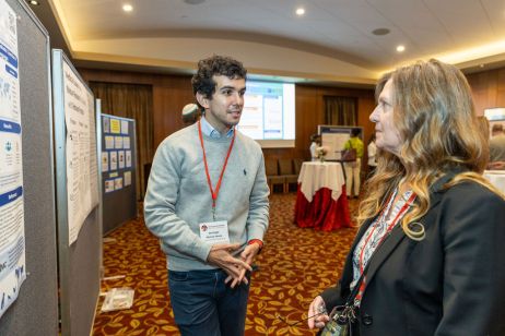 Two people speak in front of a scientific poster