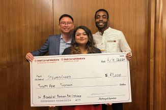 A team of two men and one woman holding a big check