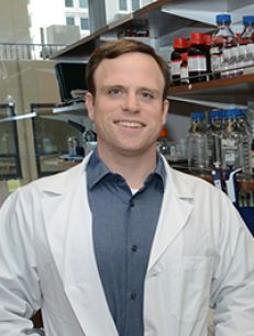 a man in a white coat smiling