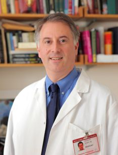 A man posing for a photo in a white coat