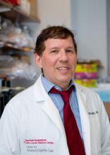 a man in a white coat smiling